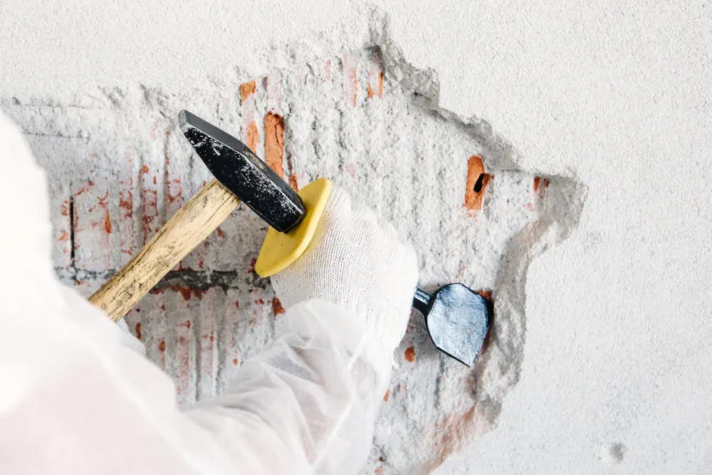 Facharbeiter entfernt mit Hammer und Meisel den Putz